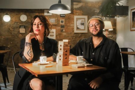 foto colorida de Pitty e Emicida sentados em mesa - metrópoles