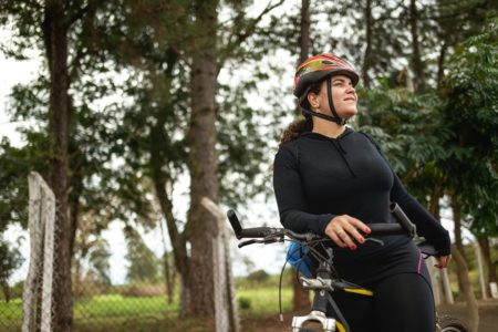 Foto colorida de uma mulher vestida com roupa de ciclista e capacete - Metrópoles