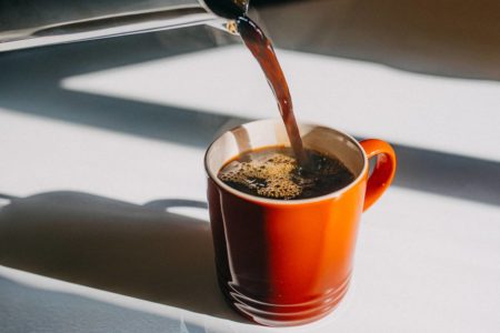 Imagem mostra café sendo despejado em uma xícada laranja - Metrópoles