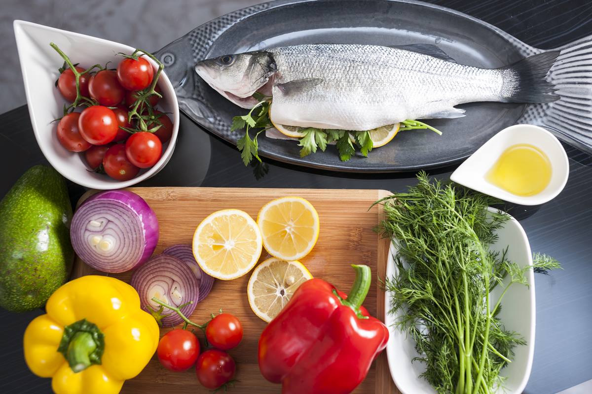 Foto colorida - alimentos saudáveis, como peixe, laranja, pimentão e tomate