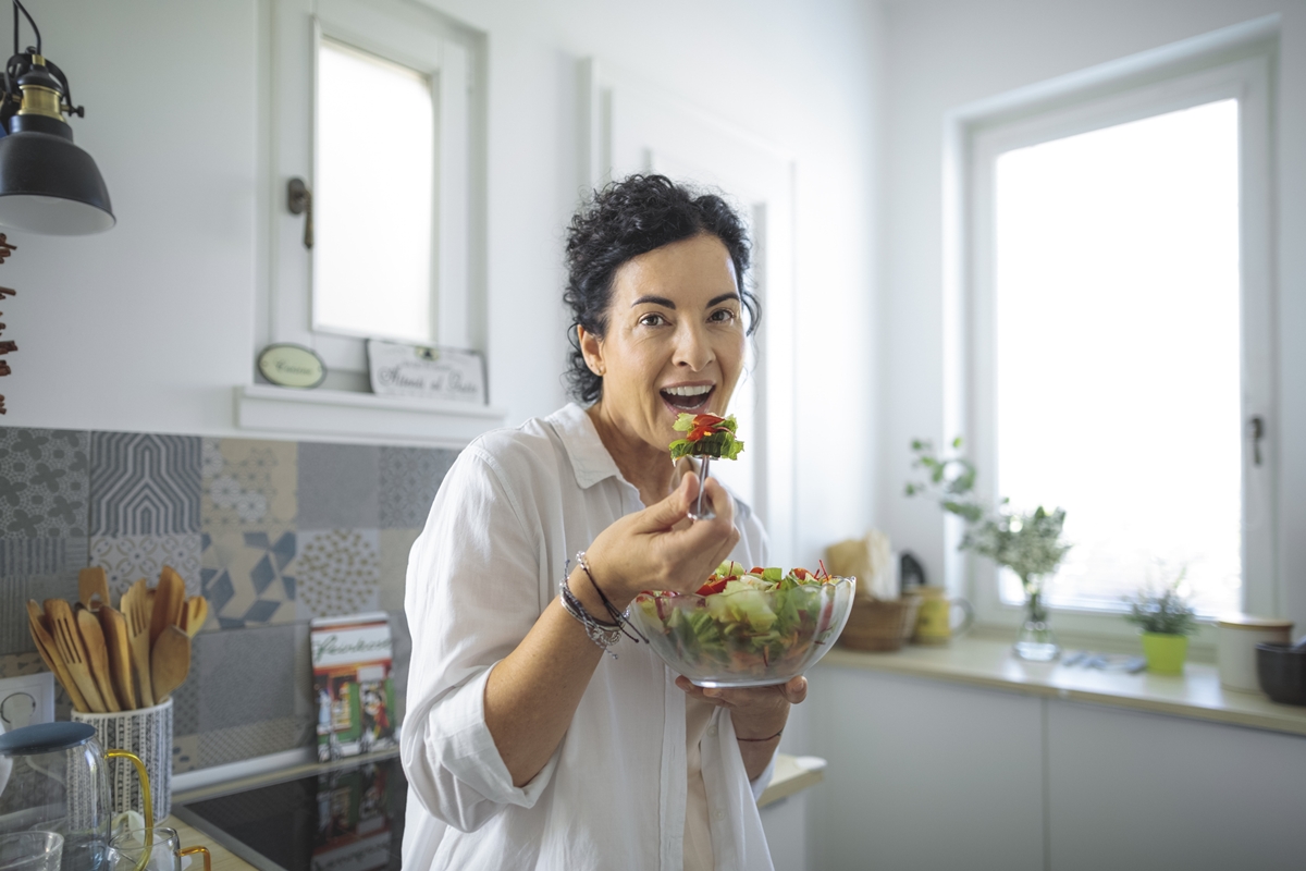 Mulher madura se alimentando na cozinha - Metrópoles