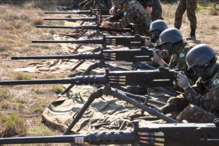 Militares com roupa camuflada lado a lado segurando metralhadoras antiaérea - Metrópoles
