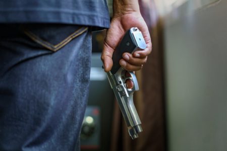 Foto colorida de homem com arma de fogo - Metrópoles