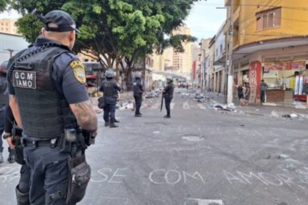 Imagem mostra homem fardado em frente a rua suja - Metrópoles