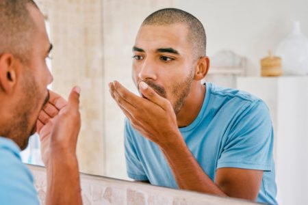 Foto de homem com mão na boca e se olhando no espelho - Metrópoles