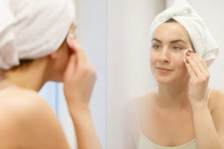 mulher aplicando produto de skincare na pele com algodão