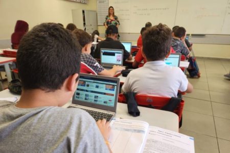 Imagem colorida mostra professora dando aula a estudantes com computadores em sala de aula de escola estadual em São Paulo - Metrópoles