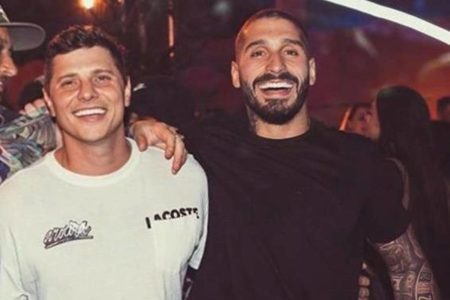 Na imagem colorida, dois homens sorriem em evento - Metrópoles