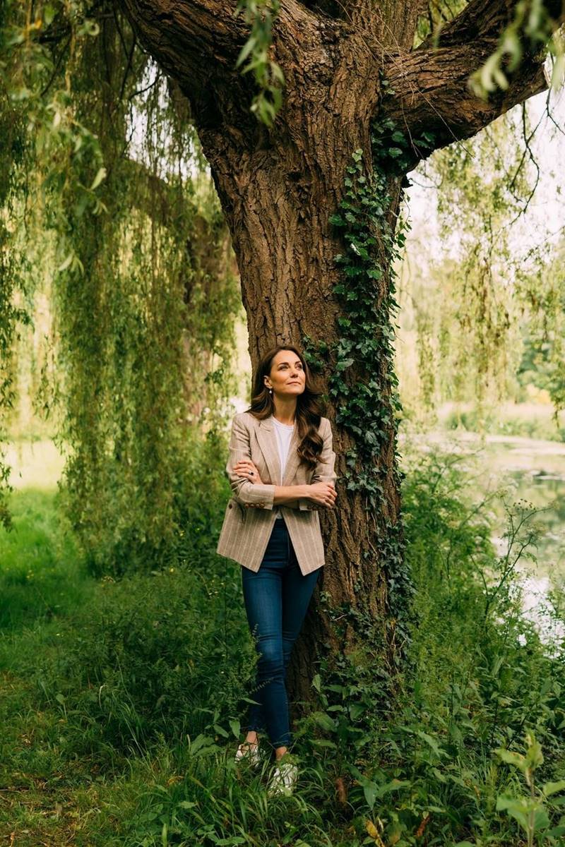 Foto colorida de mulher próximo a uma árvore e em um jardim - Metrópoles