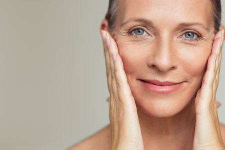mulher de olhos claros com mãos no rosto