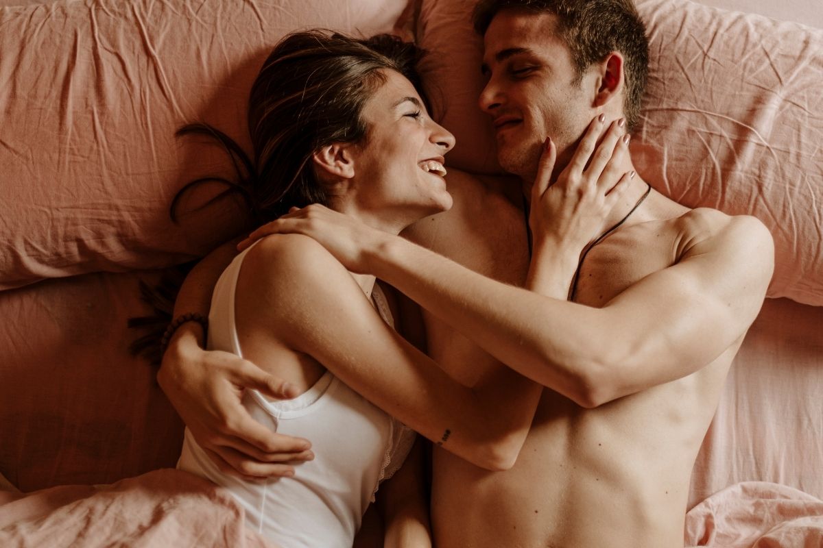 homem e mulher em cama com lençol rosa