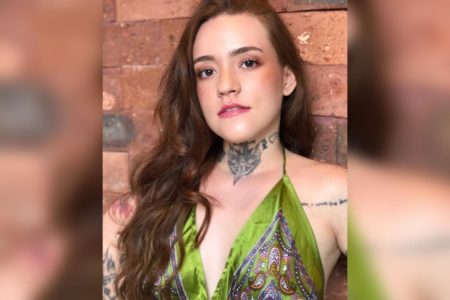Foto de Carolina Arruda Leite usando uma blusa verde decotada mostra uma tatuagem no pescoço - Metrópoles