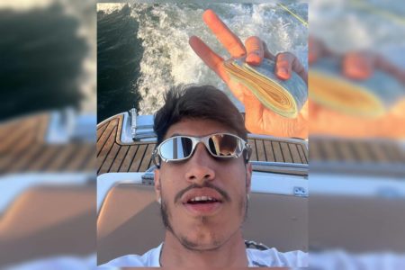 Homem jovem segurando dois bolos grande de cédulas de real
