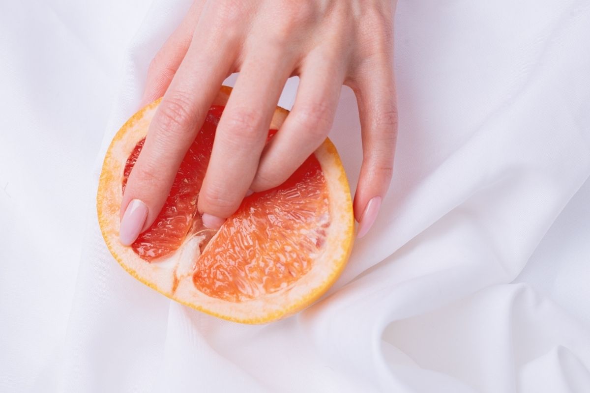 uma mão feminina cm uma laranja