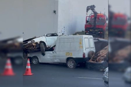 Imagem colorida de quatro carros colididos, com dois cones à frente