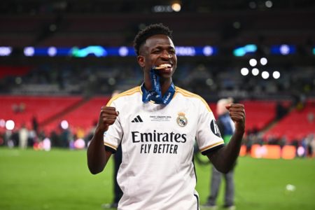Foto colorida de Vini Jr. sorrindo com a medalha da Champions League - Metrópoles