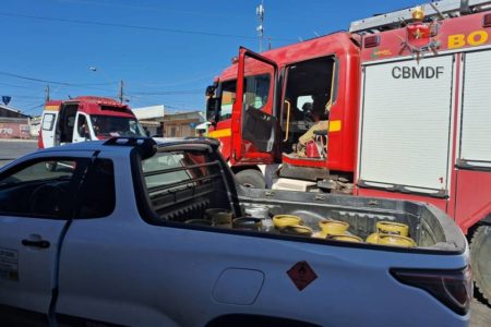 Foto colorida de caminhonete, com caçamba cheia de botijões de gás, em frente a caminhão do corpo de bombeiros