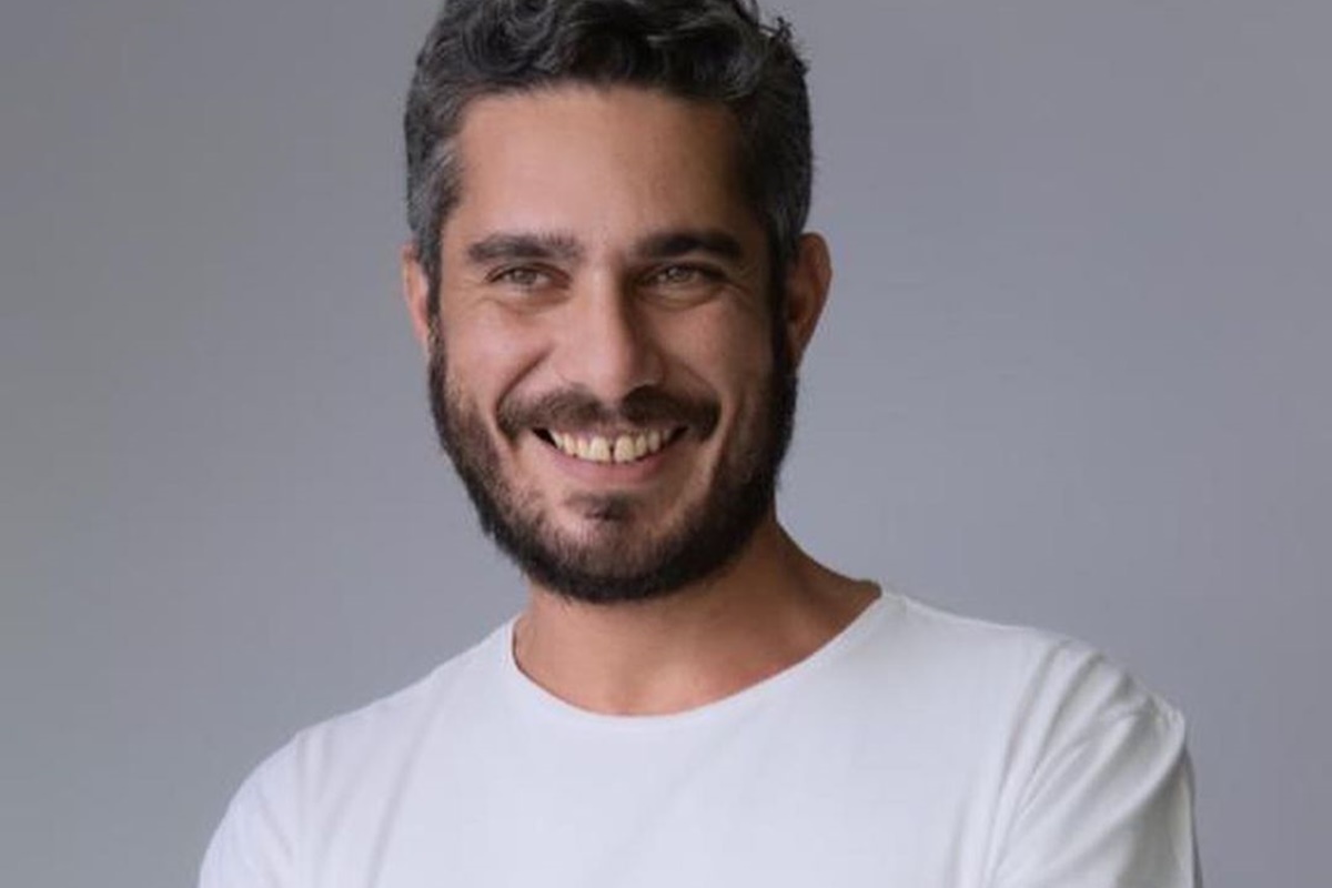 Thommy Schiavo posa, sorridente, usando uma camiseta branca - Metrópoles