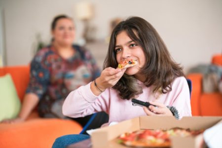 Adolescente comendo pizza enquanto joga videogame - Metrópoles