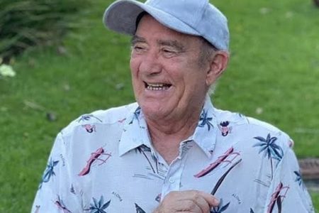 Renato Aragão é clicado com uma blusa florida e boné, dando risada - Metrópoles