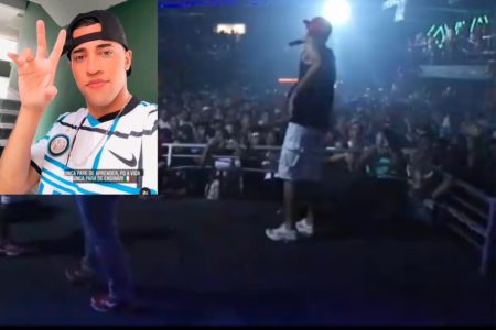 Reprodução colorida de cantor em palco iluminado, com plateia assistindo - Metrópoles
