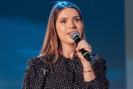 Foto colorida da cantora gospel Camila Campos com um microfone na mão - Metrópoles