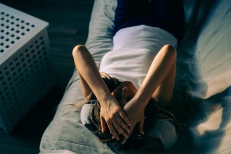 Foto mulher deitada na cama cobrindo o rosto não consegue dormir - Metrópoles