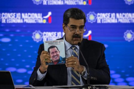 Imagem colorida mostra o presidente da Venezuela, Nicolás Maduro, segurando um livro com a foto do ex-presidente do país Hugo Chávez - Metrópoles