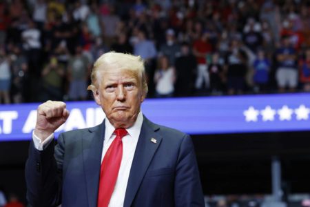 Imagem colorida mostra Donald Trump com o braço levantado e punho cerrado - Metrópoles