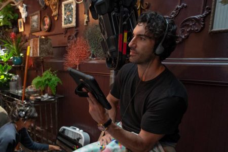 Justin Baldoni, diretor e ator do filme É Assim que Acaba, usando fone e segurando tablet enquanto segura cena do filme - Metrópoles