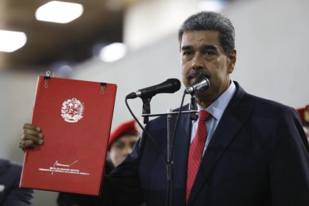 Imagem colorida mostra o presidente da Venezuela, Nicolás Maduro, segurando um caderno vermelho- Metrópoles