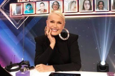 Xuxa posa, sorridente, com um look preto - Metrópoles