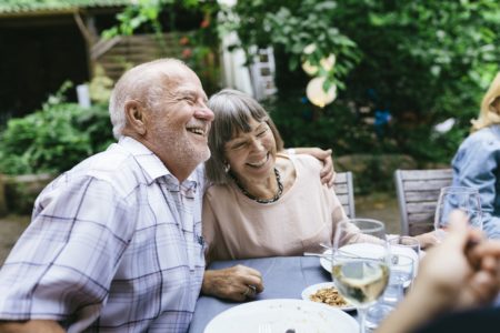 Casal de idosos desfrutando de refeição ao ar livre com a família