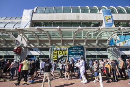 A foto colorida mostra a entrada da San Diego Comic-Con, com pessoas andando pela rua - Metrópoles