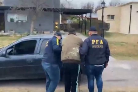 Imagem colorida mostra dois policiais argentinos conduzindo um homem para um carro - Metrópoles