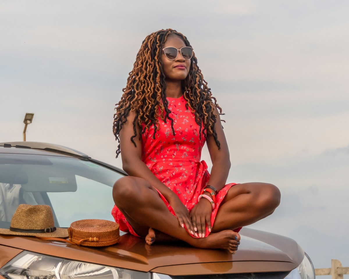 Fotografia colorida mostrando mulher sentada em capô de carro-Metrópoles