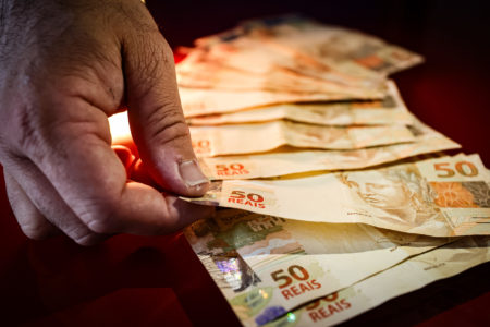 Imagem colorida mão com dinheiro pagamento moeda papel - Metrópoles