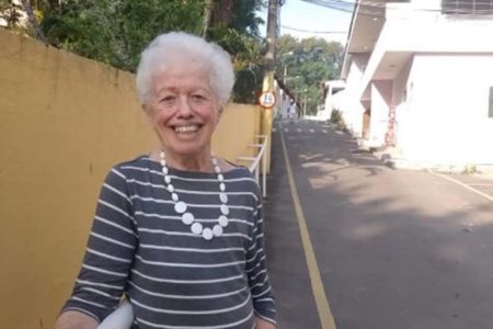 foto colorida de uma mulher idosa sorrindo com blusa listrada - metrópoles