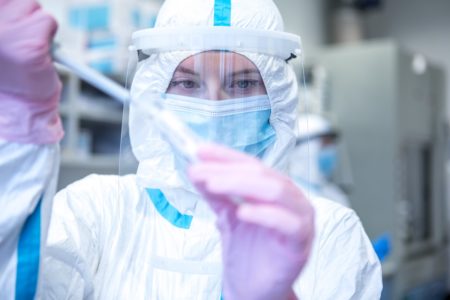 Imagem mostra mulher com equipamento de proteção mexendo em uma seringa, representando estudos científicas contra uma pandemia - Metrópoles