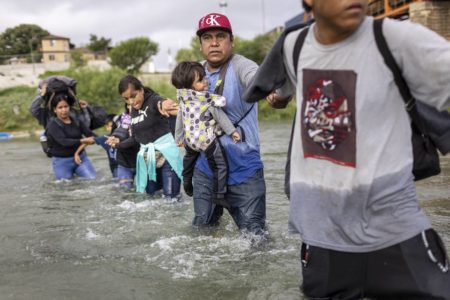 Imagem colorida mostra imigrantes venezuelanos em um rio - Metrópoles