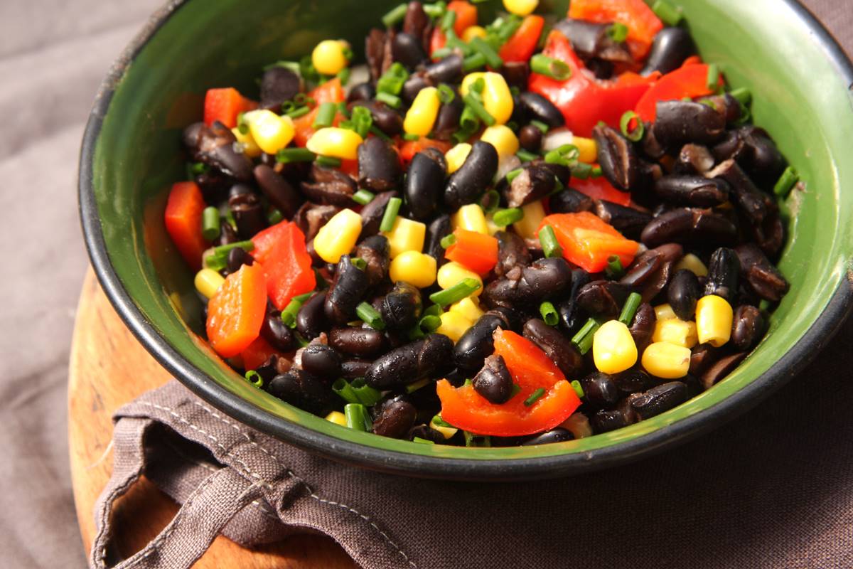 Foto colorida de salada de tomate, feijão-preto, salsinha e milho - Metrópoles