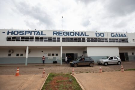 Imagem colorida da fachada do Hospital Regional do Gama, com o nome escrito em tinta preta na parede