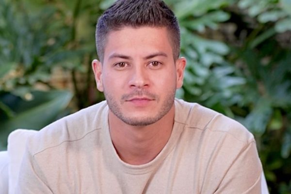 Arthur Aguiar posa sério, de camiseta bege, para publicidade - Metrópoles