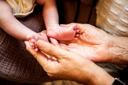 Foto colorida de um bebê e uma idosa - Metrópoles