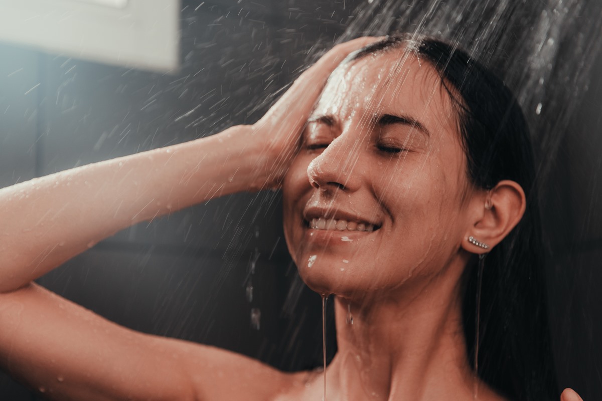 Foto colorida de mulher debaixo do chuveiro, tomando banho - Metrópoles