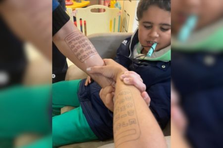 Foto colorida Felipe vendo tatuagem dos pais - Metrópoles