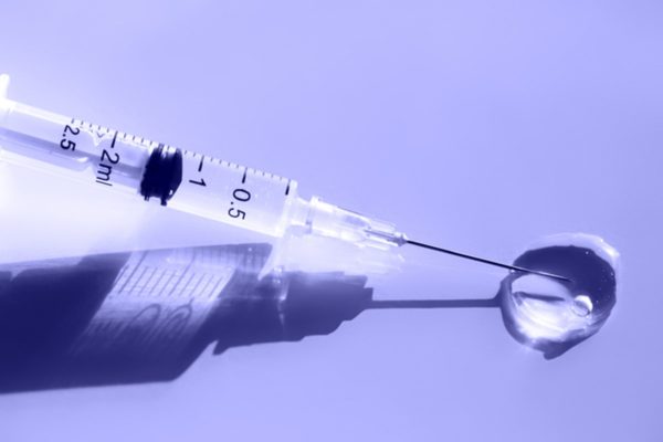 Vacina em fundo roxo, com gora na agulha - Metrópoles