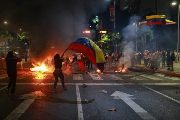 Imagem colorida mostra mulher segurando bandeira da Venezuela - Metrópoles