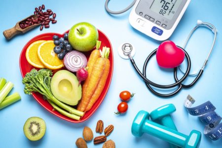 Conceitos de estilo de vida saudável: placa em forma de coração vermelho com frutas e legumes orgânicos frescos, filmados em fundo azul. Ao lado do prato estão monitor digital de pressão arterial, estetoscópio médico, halteres e fita métrica. Esse tipo de alimento é rico em antioxidantes e flavonóides que previnem doenças cardíacas, reduzem o colesterol e ajudam a manter uma alimentação equilibrada. Captura digital de estúdio de alta resolução de 42Mp feita com lente SONY A7rII e Zeiss Batis 40mm F2.0 CF
