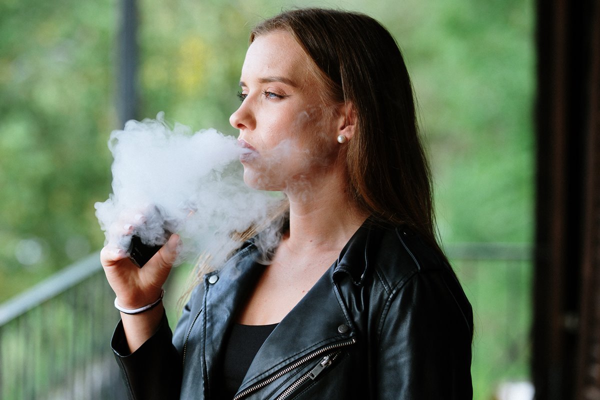 Foto colorida de mulher fumando vape - Metrópoles